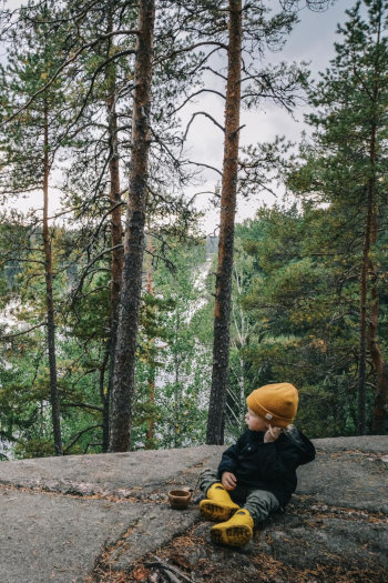 Nuori retkeilijä metsäisellä kalliolla.